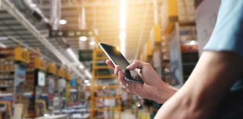 Apps und AddOns für mehr Flexibilität Mann vor Lagerkulisse mit Smartphone