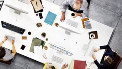 Effizienter arbeiten mit funktioneller PM-App Projektgruppe um Tisch sitzend