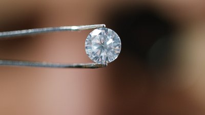 Diamant in einer Pinzette als Symbol für Qualität mit Link zu SAP-Lösungen für das Qualitätsmanagement.